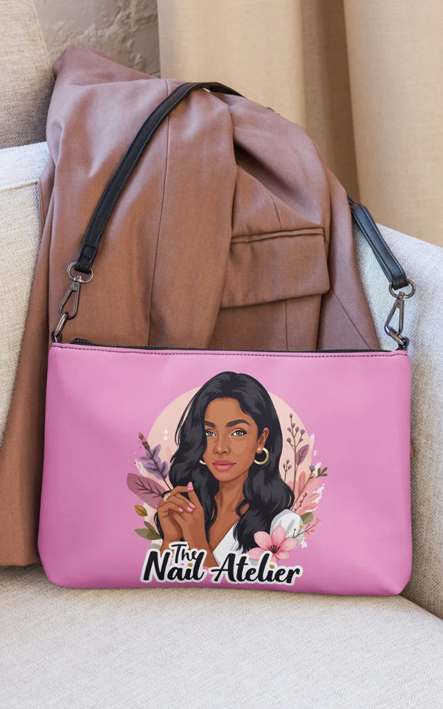 The nail tech cartoon logo for The Nail Atelier on a stylish pink handbag.